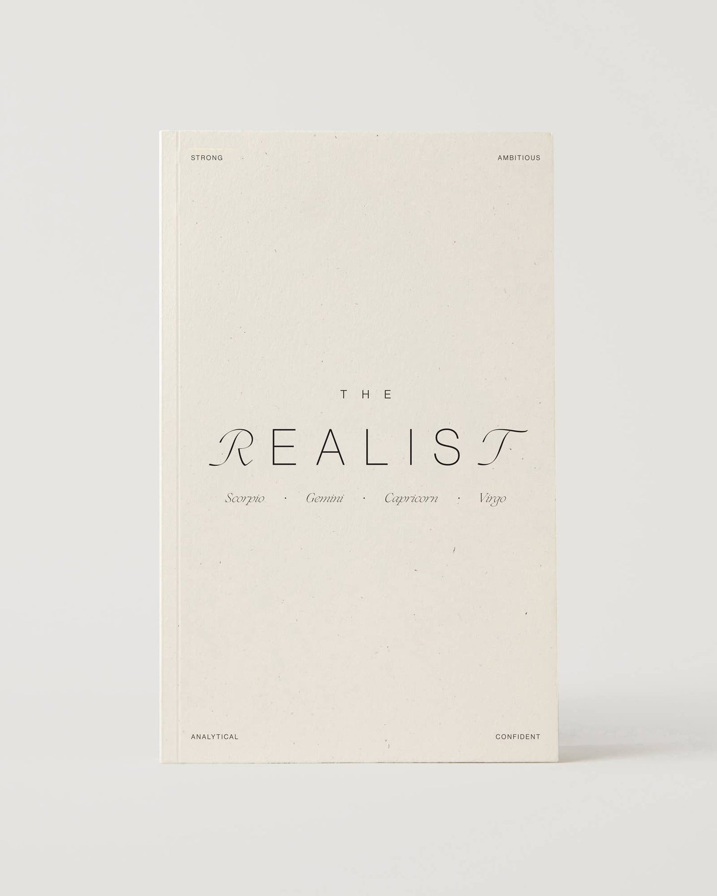 Cream-coloured minimalist journal titled “The Realist” with poetic zodiac references on the cover – a lined astrology-inspired notebook made with recycled paper.