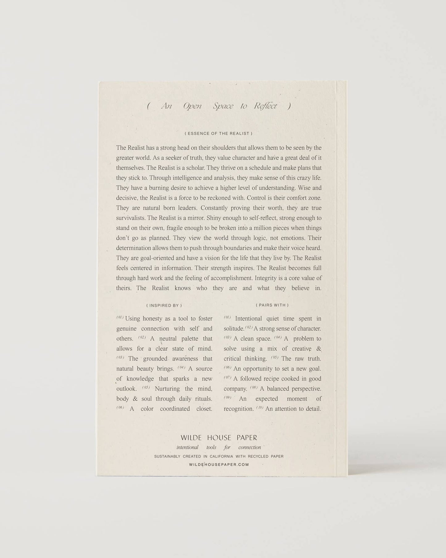 Cream-coloured minimalist journal titled “The Realist” with poetic zodiac references on the cover – a lined astrology-inspired notebook made with recycled paper.