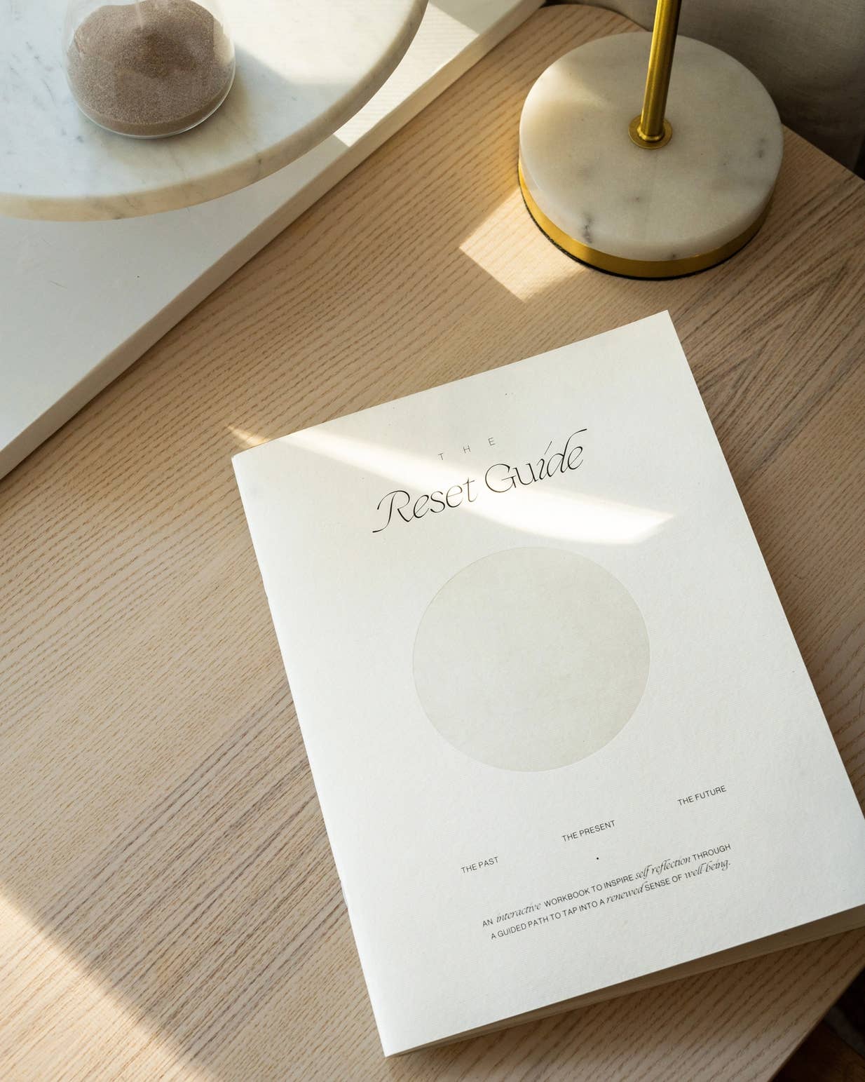 Minimalist beige guided journal titled "The Reset Guide" with soft circular design, created for personal growth and self-reflection through past, present, and future prompts.