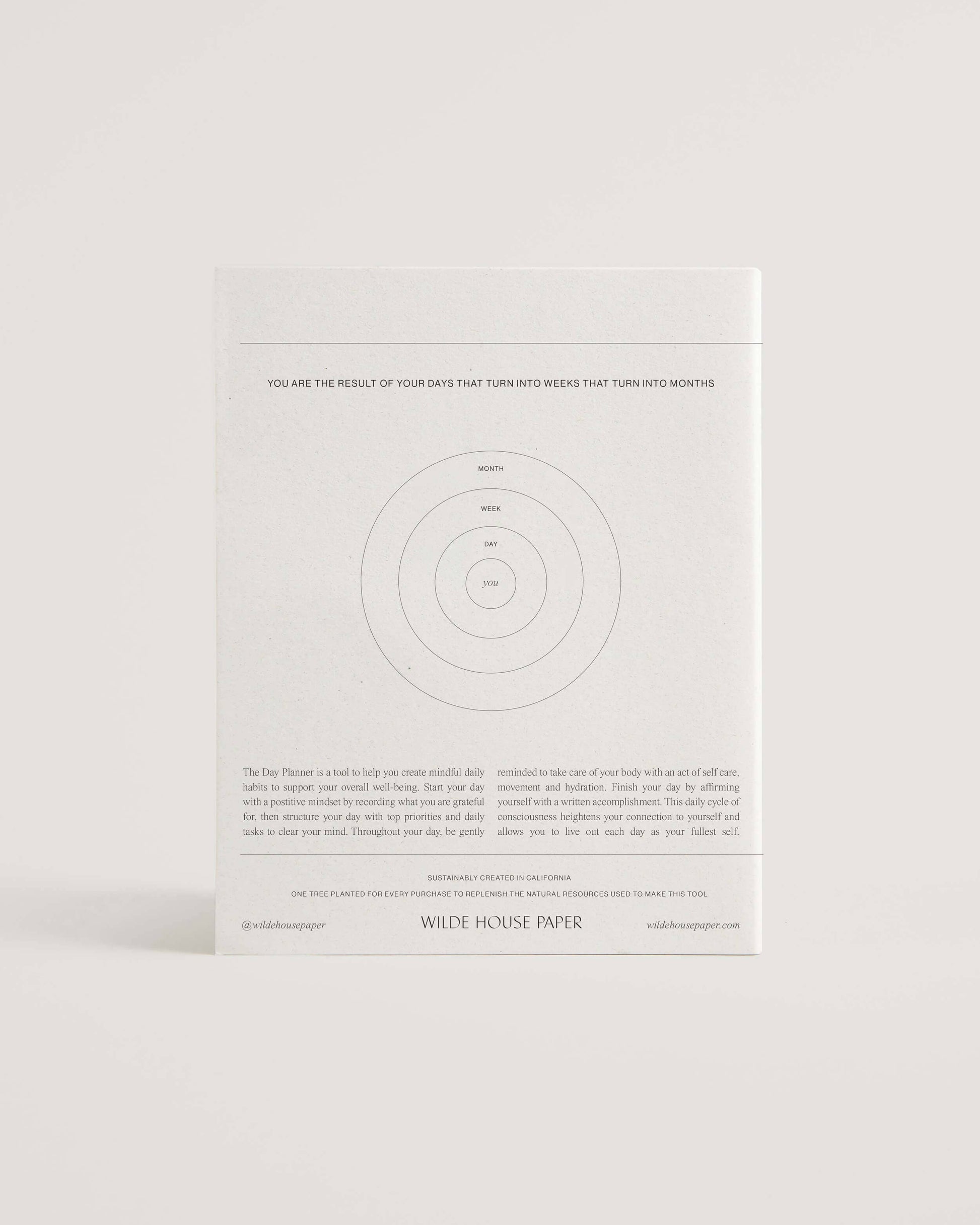 Minimalist white undated daily planner with circular design and wellness prompts on the cover – ideal for tracking gratitude, self-care and daily priorities.