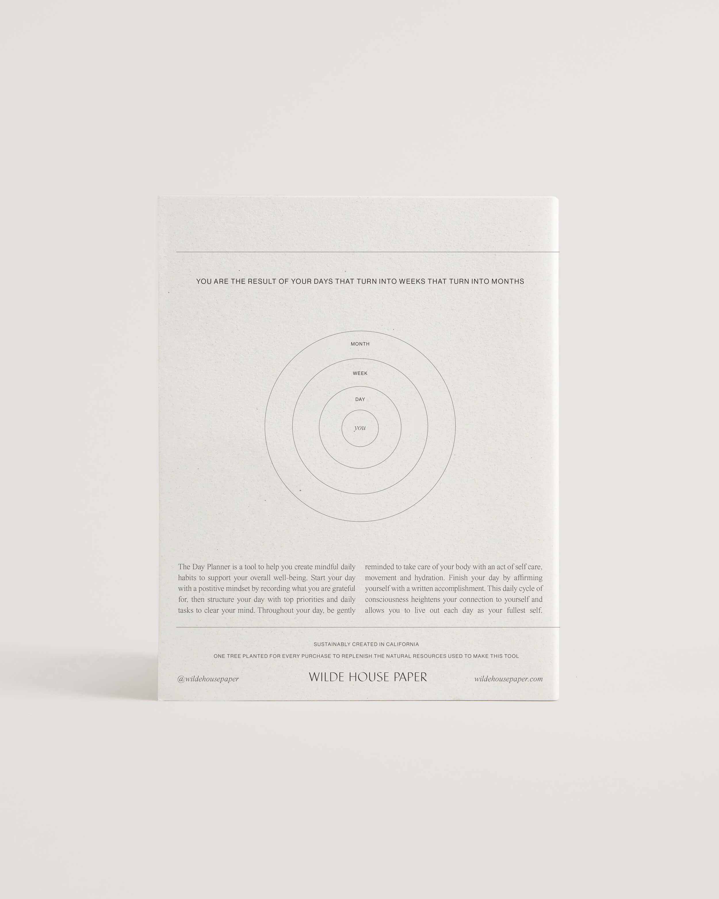 Minimalist white undated daily planner with circular design and wellness prompts on the cover – ideal for tracking gratitude, self-care and daily priorities.