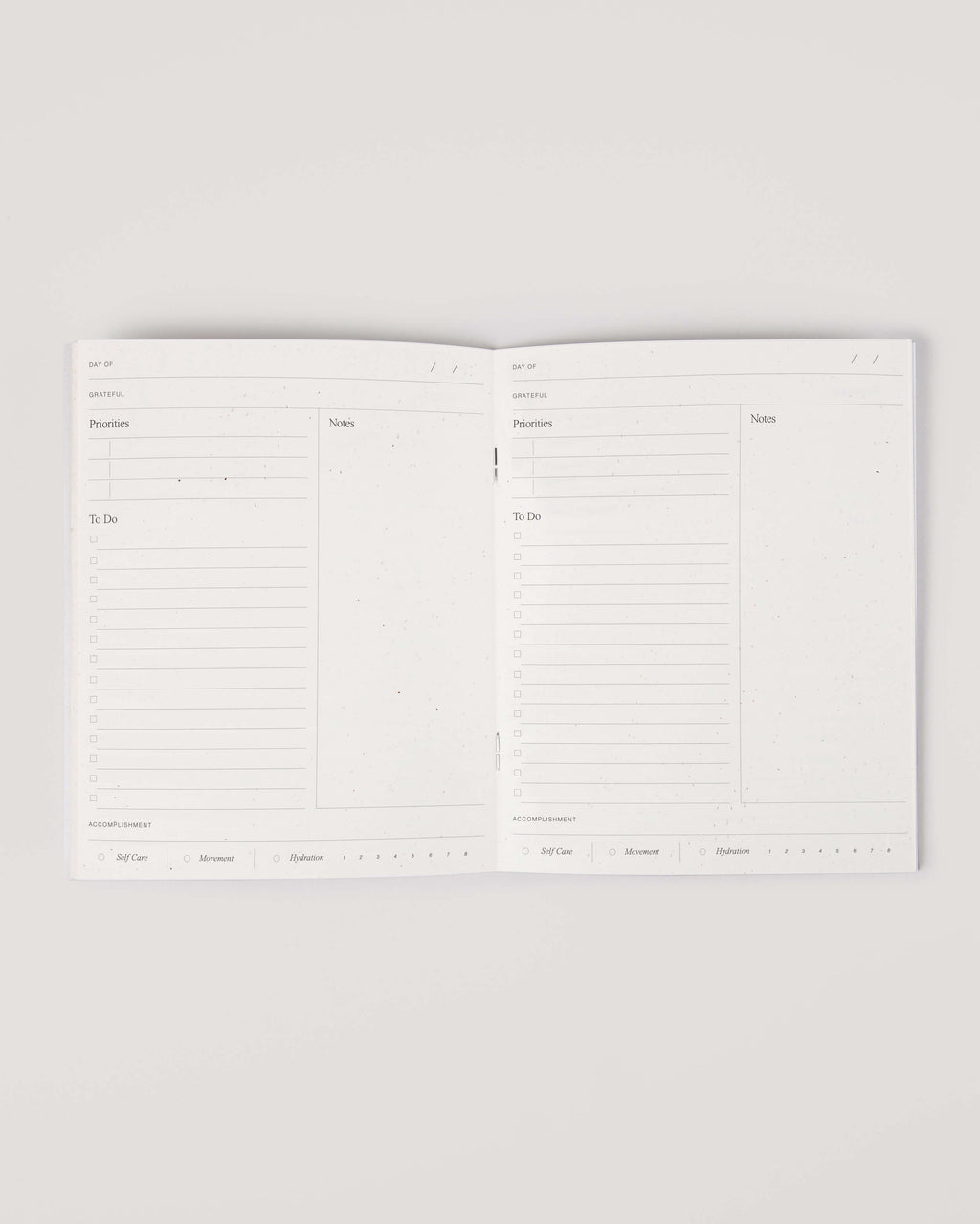 Minimalist white undated daily planner with circular design and wellness prompts on the cover – ideal for tracking gratitude, self-care and daily priorities.