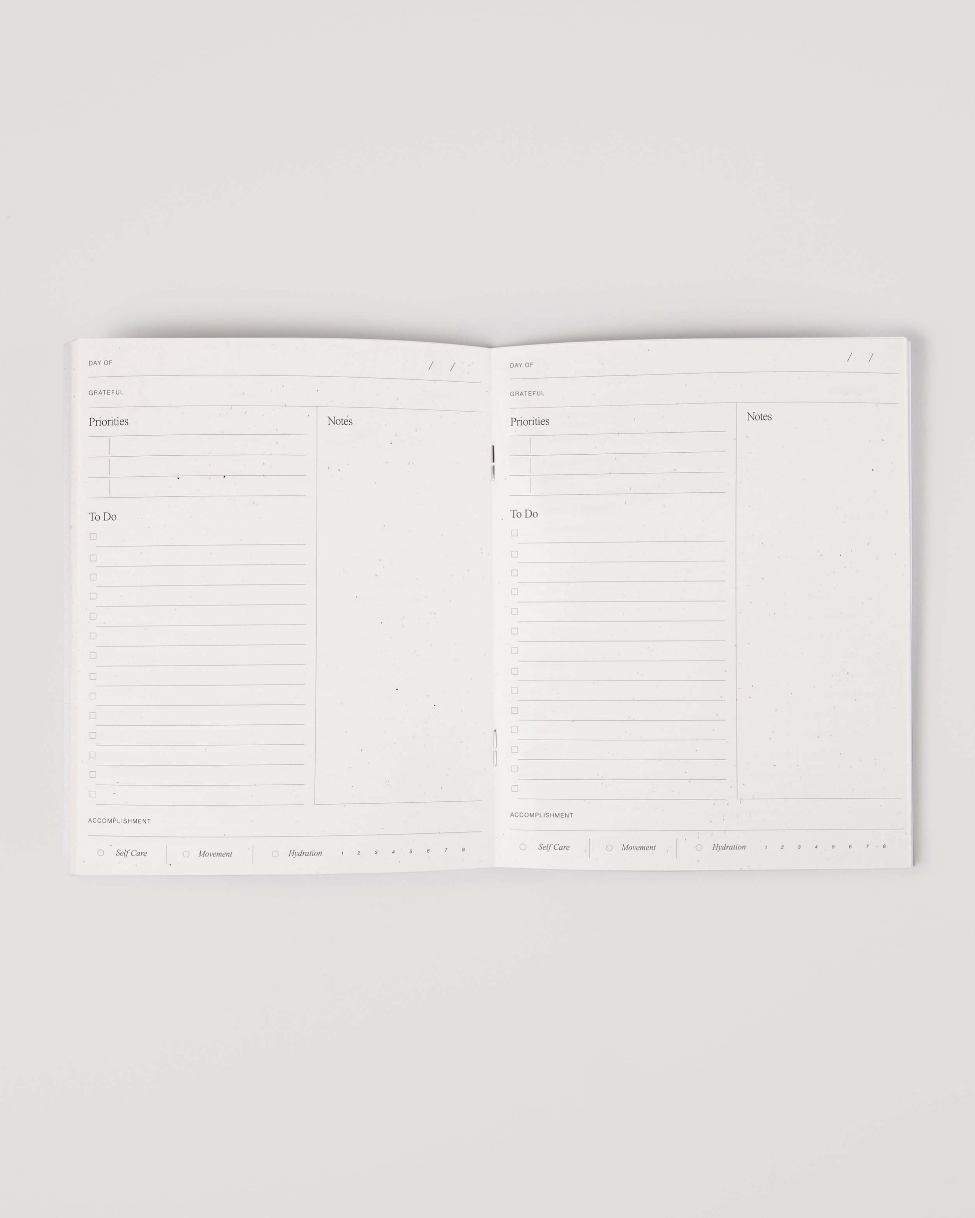 Minimalist white undated daily planner with circular design and wellness prompts on the cover – ideal for tracking gratitude, self-care and daily priorities.
