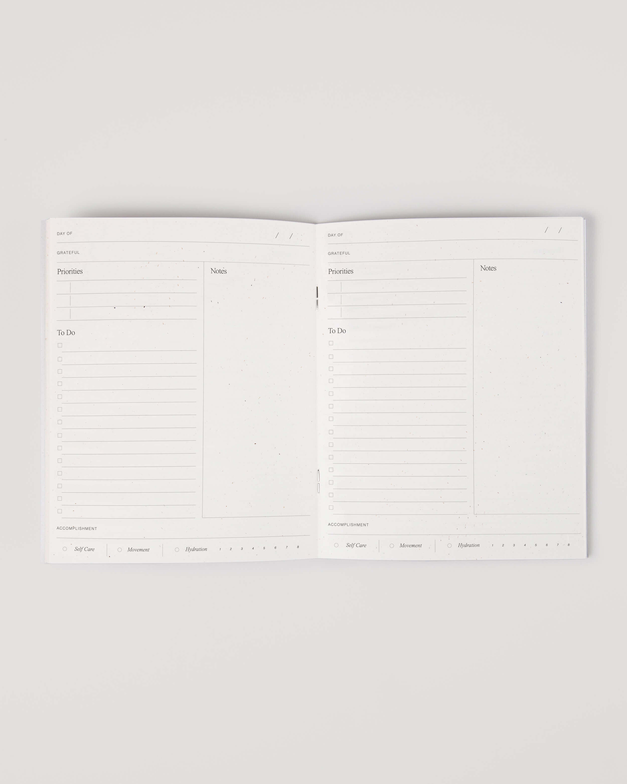 Minimalist white undated daily planner with circular design and wellness prompts on the cover – ideal for tracking gratitude, self-care and daily priorities.