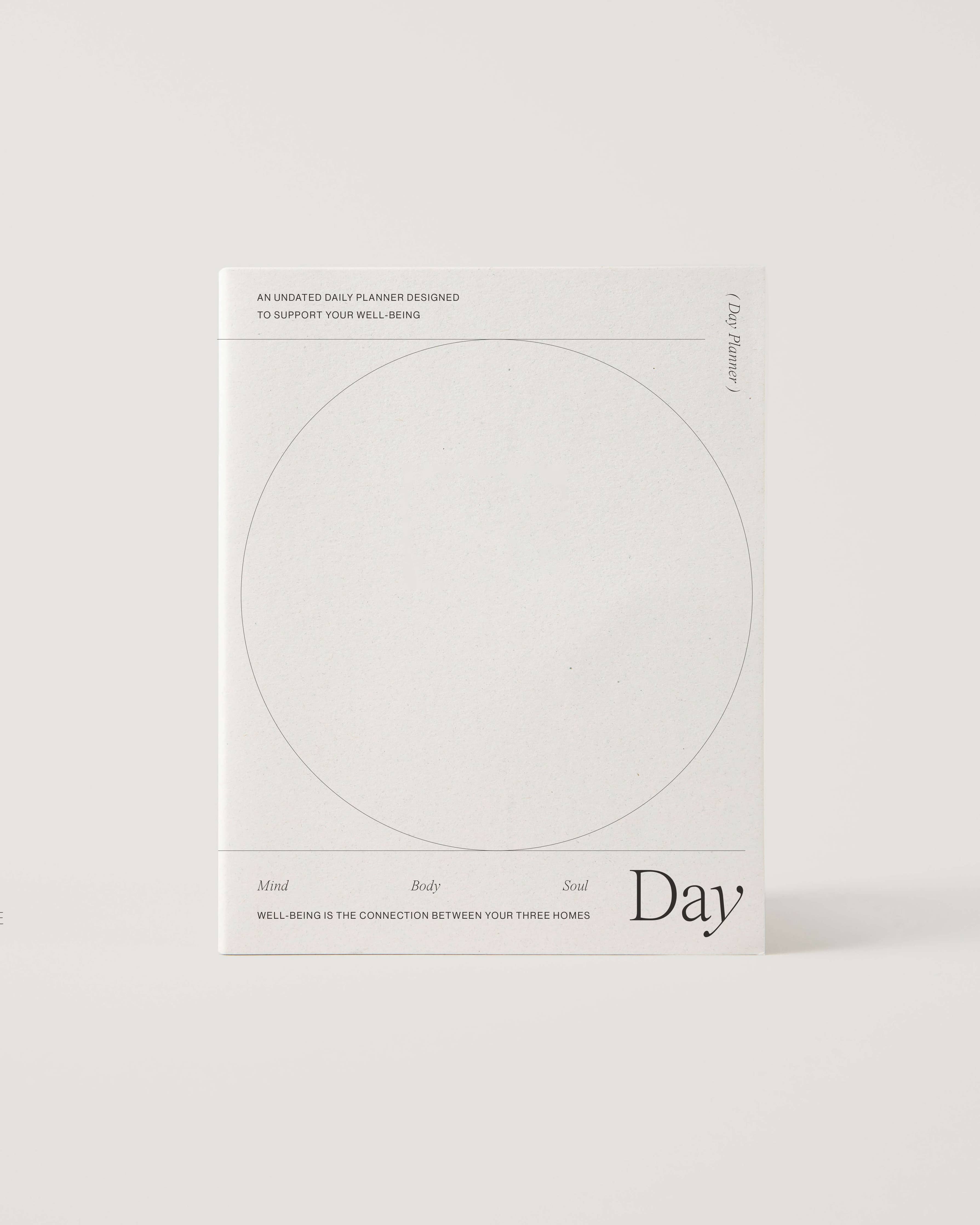 Minimalist white undated daily planner with circular design and wellness prompts on the cover – ideal for tracking gratitude, self-care and daily priorities.
