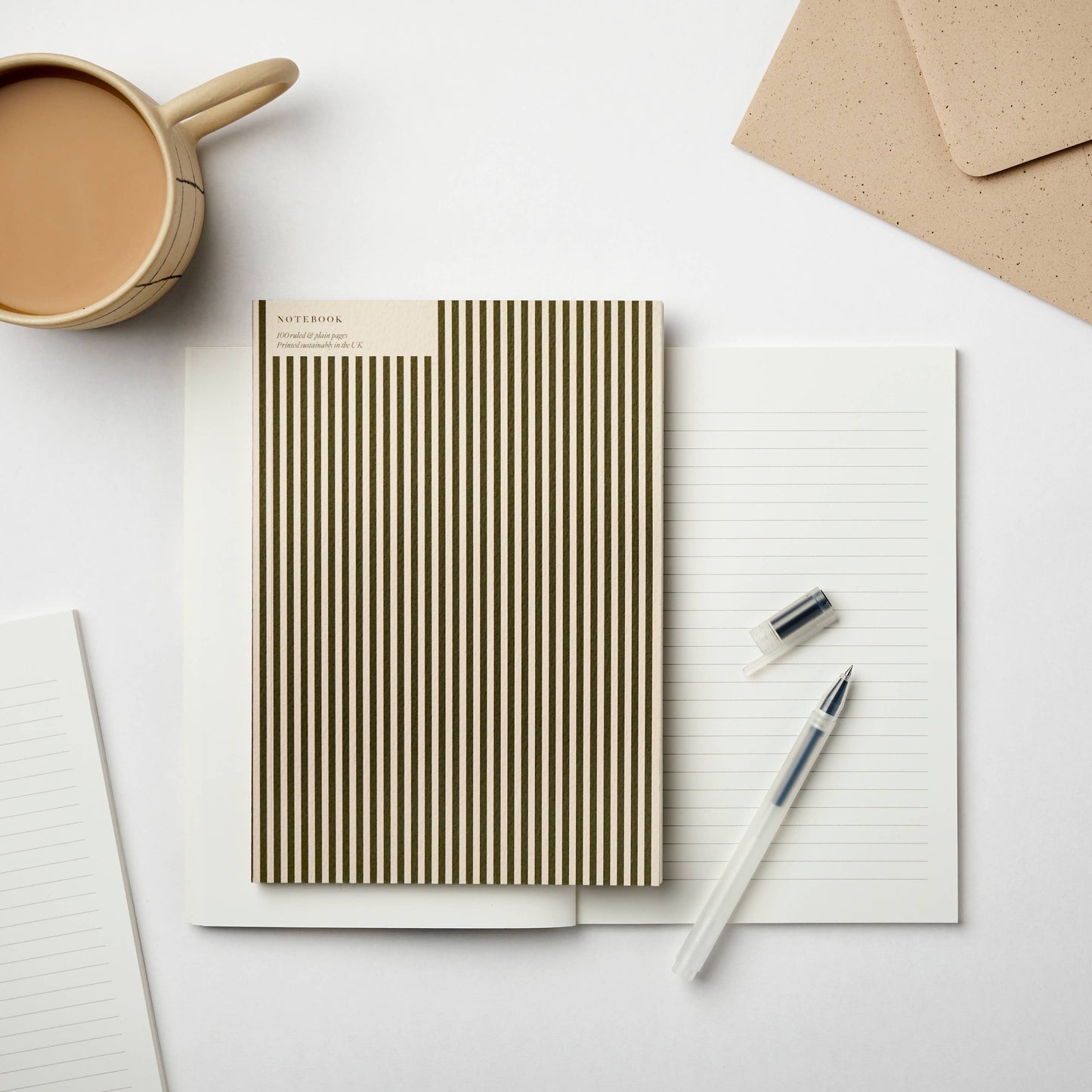 Green and cream vertical stripe A5 notebook on lined paper background with pen and coffee – ideal for journaling, sketching and mindful note-taking.