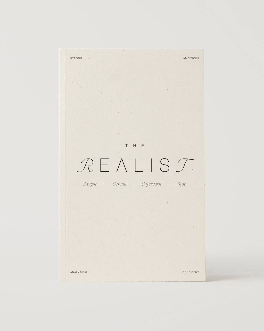 Cream-coloured minimalist journal titled “The Realist” with poetic zodiac references on the cover – a lined astrology-inspired notebook made with recycled paper.