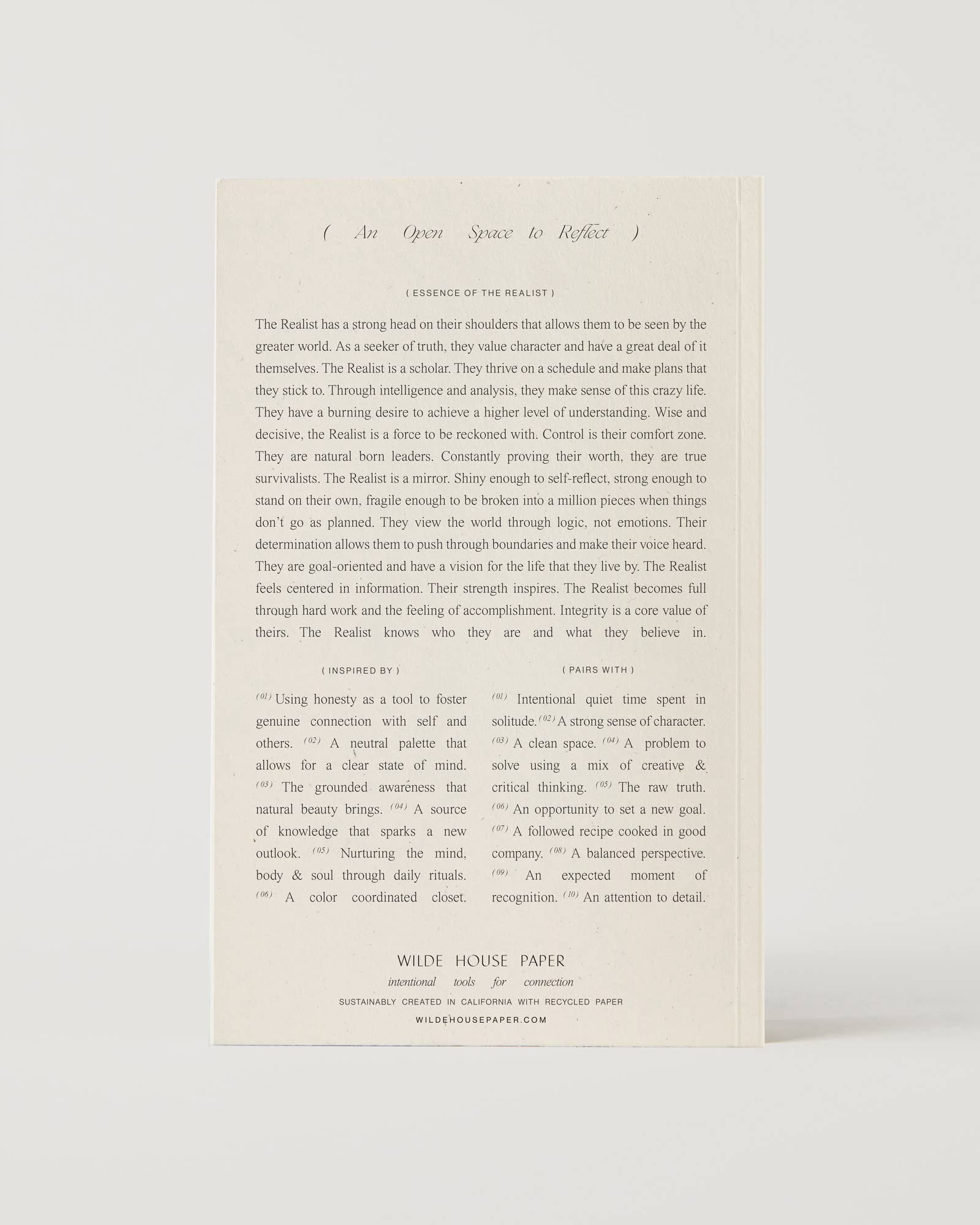 Cream-coloured minimalist journal titled “The Realist” with poetic zodiac references on the cover – a lined astrology-inspired notebook made with recycled paper.